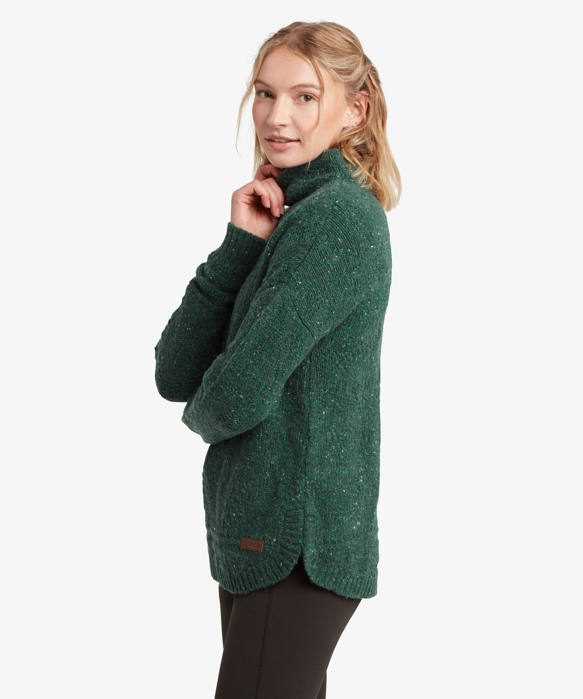 A female model, shown from the side, wearing the green Yuden Sweater by Sherpa Adventure Gear.