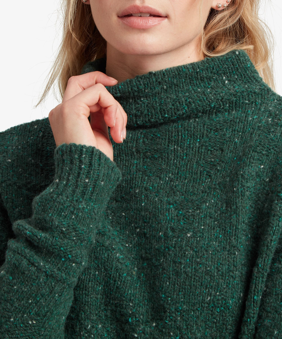 A female model wearing the green Yuden Sweater by Sherpa Adventure Gear, shown in close-up.